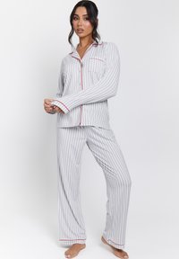 Gray and white striped pajama set with red accents. Features long sleeves, a button-up top with pocket, and loose-fitting pants.