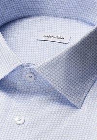 Lichtblauw overhemd met een subtiele stippenpatroon. Voorzien van een button-down kraag en witte knopen. Etiket zegt "seidensticker."