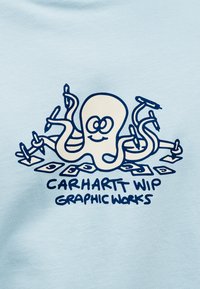 Ανοιχτό μπλε βαμβακερό T-shirt με καρτούν χταπόδι που κρατάει στυλό και χαρτί, με περίγραμμα σε ναυτικό μπλε, και το κείμενο «Carhartt WIP Graphic Works» από κάτω.