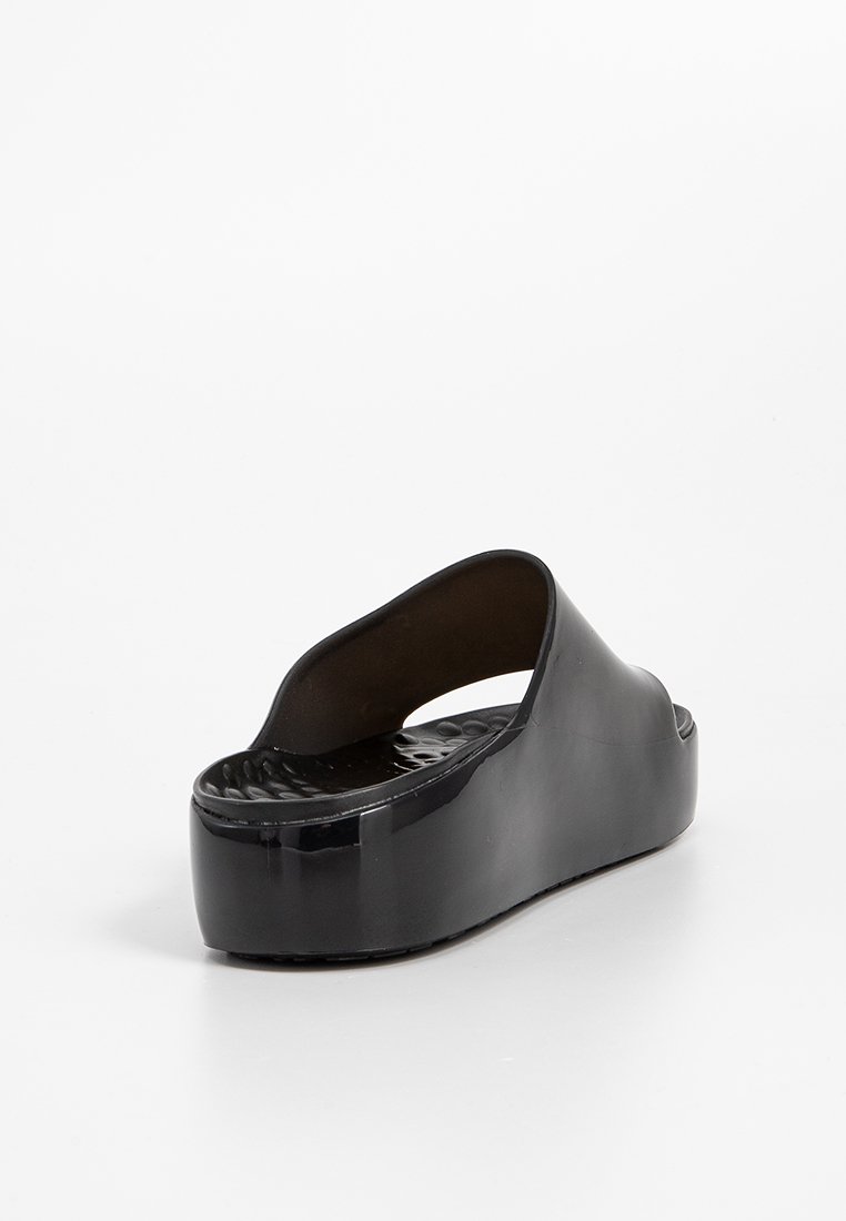 Schwarze Plateausandale mit glänzender Oberfläche, offenem Rücken, geschwungenem Oberteil und strukturiertem Fußbett für besseren Halt. Elegantes Design ohne zusätzliche Verzierungen.