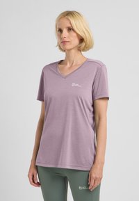T-shirt a maniche corte di colore viola chiaro con scollatura a V, dotato di un piccolo logo sul lato sinistro del petto e tessuto liscio e traspirante.