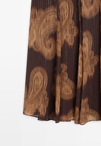 Gonna di tessuto marrone con un motivo paisley in oro. Presenta linee verticali e un design fluido. L'orlo è leggermente curvo.