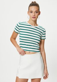 Vihreä ja valkoinen raidallinen lyhyet hiha crop-top, pehmeä kangas, pyöreä pääntie. Yhdistetty korkeavyötäröisen valkoisen mini-hameen kanssa.
