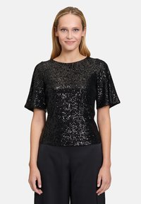 Schwarzes Paillettenoberteil mit kurzen Ärmeln, rundem Ausschnitt und eng anliegender Silhouette. Glänzende Textur mit unterschiedlichen Paillettenmustern.