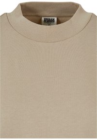 Beige økologisk bomull genser med ribbestrikket rund hals og glatt tekstur. Merket leser "Urban Classics" med størrelse XS synlig.