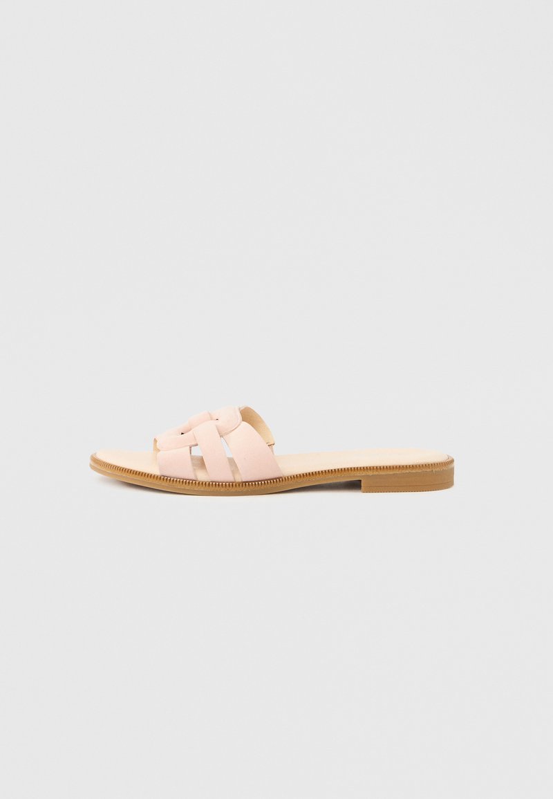 Sandales plates roses avec un design à bretelles croisées, une matière supérieure lisse et une semelle fine beige. Construction minimaliste et légère.