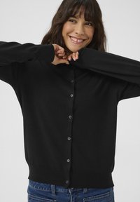 Cardigan nero in maglia con taglio dritto, dotato di chiusura a bottoni frontale, maniche lunghe e polsini e orlo a coste.