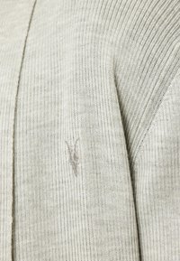 Cardigan a coste grigio chiaro con logo ricamato discreto. Il tessuto appare strutturato con delicate linee verticali.