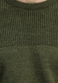 Jersey de color verde oliva con un patrón de ribete texturizado en la sección superior y un panel inferior liso. Presenta un cuello redondo.