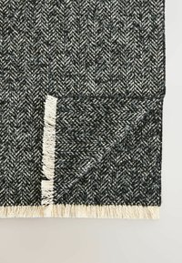 Woven black and white herringbone-patterned rug with fringed edges, showcasing textured fabric and a geometric design.