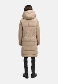 Cappotto imbottito beige con vita regolata, cappuccio grande e motivo trapuntato verticale. Presenta maniche lunghe e arriva sotto il ginocchio.