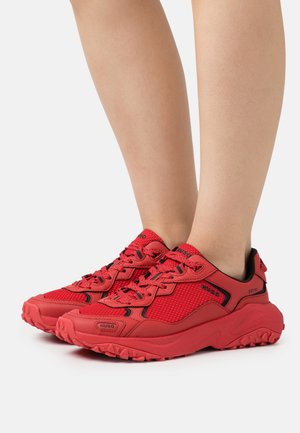 Zapatillas deportivas rojas con parte superior de malla, suela de goma y detalles en negro. Incluyen cordones y una suela texturizada para mayor agarre. Diseñadas para uso al aire libre.