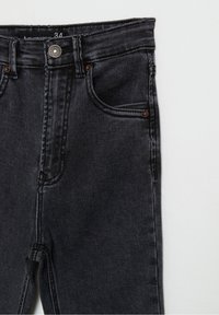 Jean en denim noir avec une taille mi-haute, un design à cinq poches, des accents de rivets en ton cuivre et un léger délavage sur le tissu.