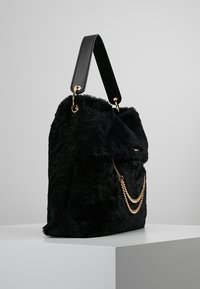 Czarna torebka z futra syntetycznego o teksturowanym wykończeniu, z akcentem w postaci złotego łańcuszka oraz czarnym skórzanym paskiem, prostokątna w kształcie z klapką zakrywającą.