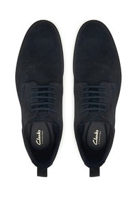Scarpe da uomo in camoscio blu navy con lacci, punta tondeggiante, superficie testurizzata e lacci scuri a contrasto. Presentano una linguetta sul tallone e una soletta con marchio.
