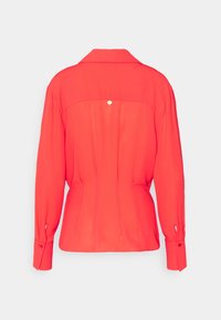 Blusa rossa a maniche lunghe con vestibilità aderente, dotata di spallina sul retro, chiusura a bottoni e polsini con dettagli a bottoni. Tessuto liscio.