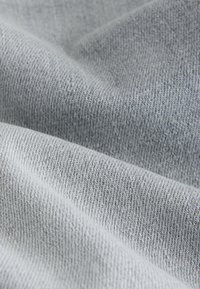 Tessuto grigio chiaro con superficie morbida e strutturata, che presenta un motivo di tessitura sottile e una finitura liscia.