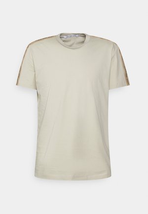 Beżowy T-shirt z krótkim rękawem, okrągłym dekoltem i markowym paskiem wzdłuż szwów na ramionach.