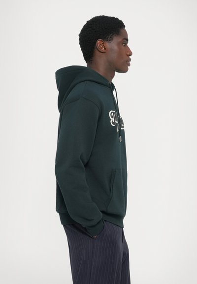 Dark green hoodie, soft texture, features a front pocket and drawstring hood; accented with white embroidered text on the chest.