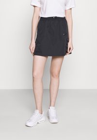 Czarna spódnica wykonana z lekkiego materiału, z elastycznym paskiem w talii, dwoma bocznymi kieszeniami i małym logo z przodu.