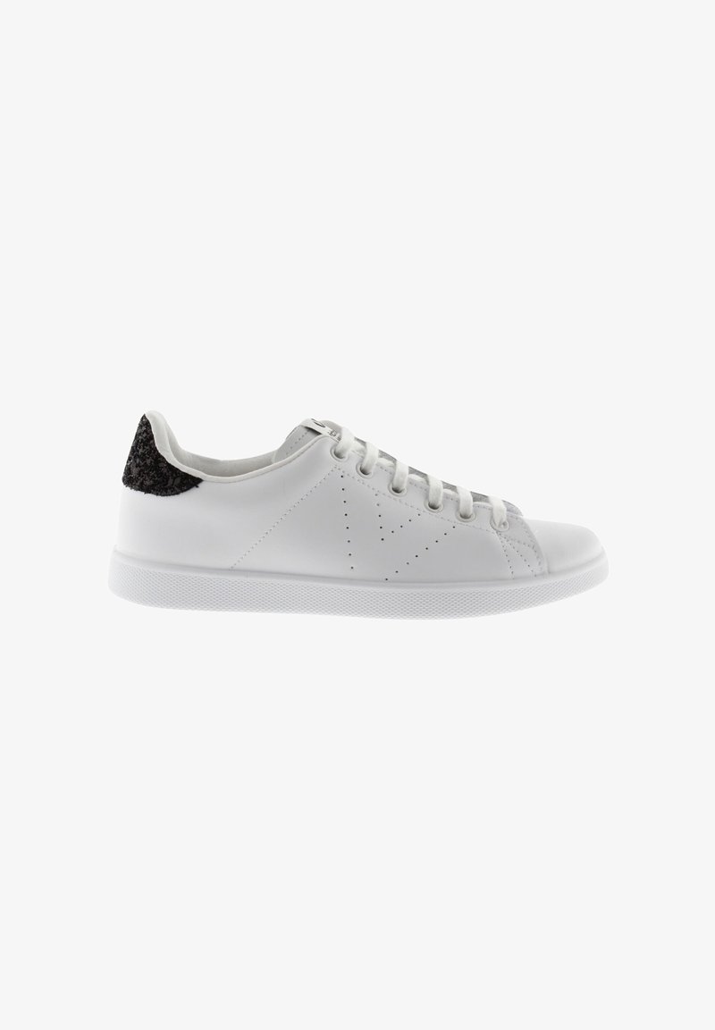 Zapatilla blanca de cuero con un acento en el talón de cuero negro texturizado. Presenta un diseño perforado, cordones planos y una suela de goma. Textura general suave.