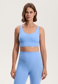 Svetlo modra športna modrca in ujemajoče se legice visoke pasu, izdelane iz gladkega, raztegljivega materiala s preprostim dizajnom in brez vidnih vzorcev ali dodatkov.