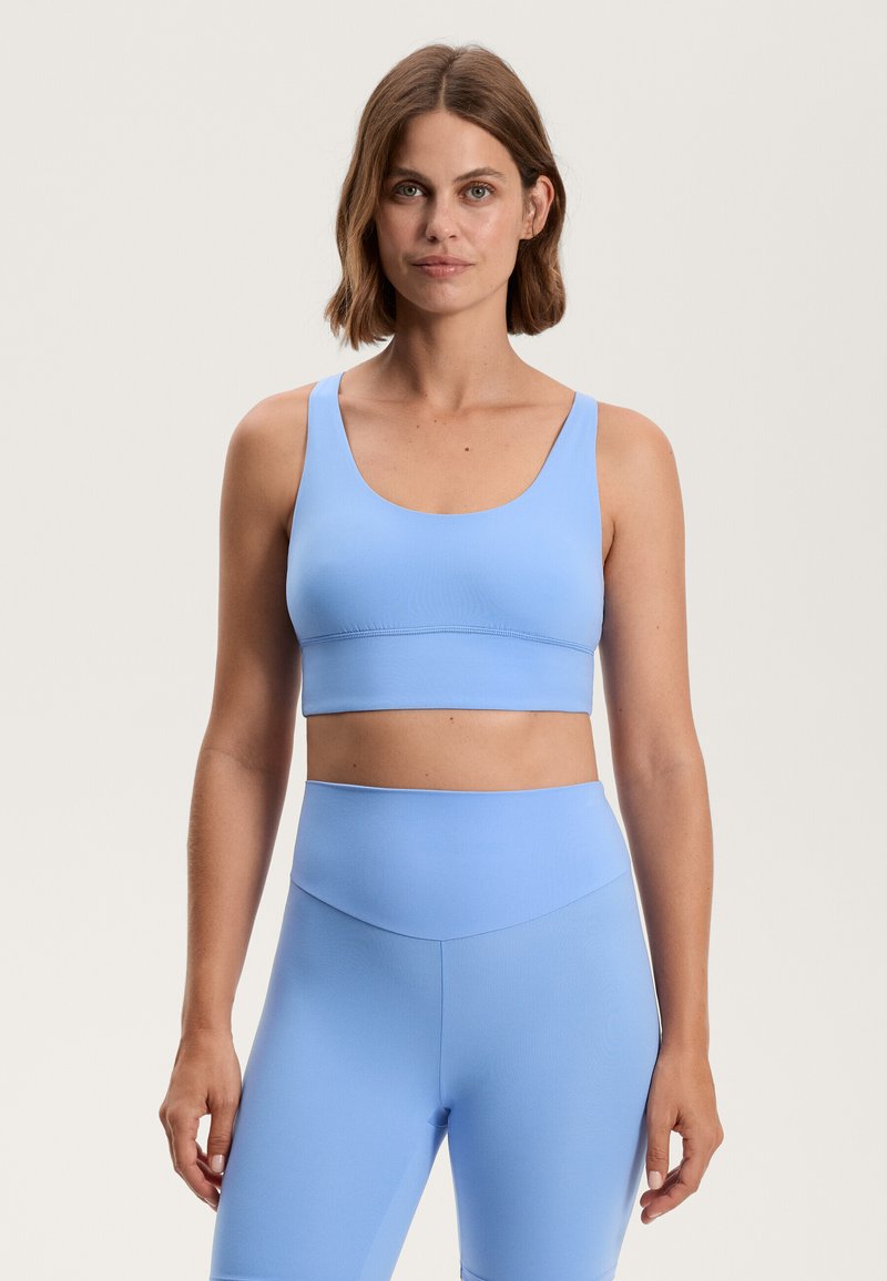 Svetlo modra športna modrca in ujemajoče se legice visoke pasu, izdelane iz gladkega, raztegljivega materiala s preprostim dizajnom in brez vidnih vzorcev ali dodatkov.