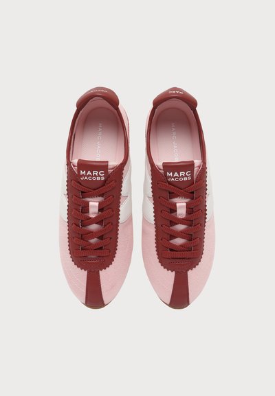 Paire de baskets Marc Jacobs roses et rouges avec des bandes latérales blanches en zigzag, vues de dessus, lacets rouges et logo sur la languette.