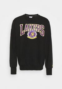 Sudadera negra con la inscripción "LAKERS" en letras en negrita moradas y amarillas, un logo circular y puños y dobladillo de canalé. Logo de Nike en la manga.