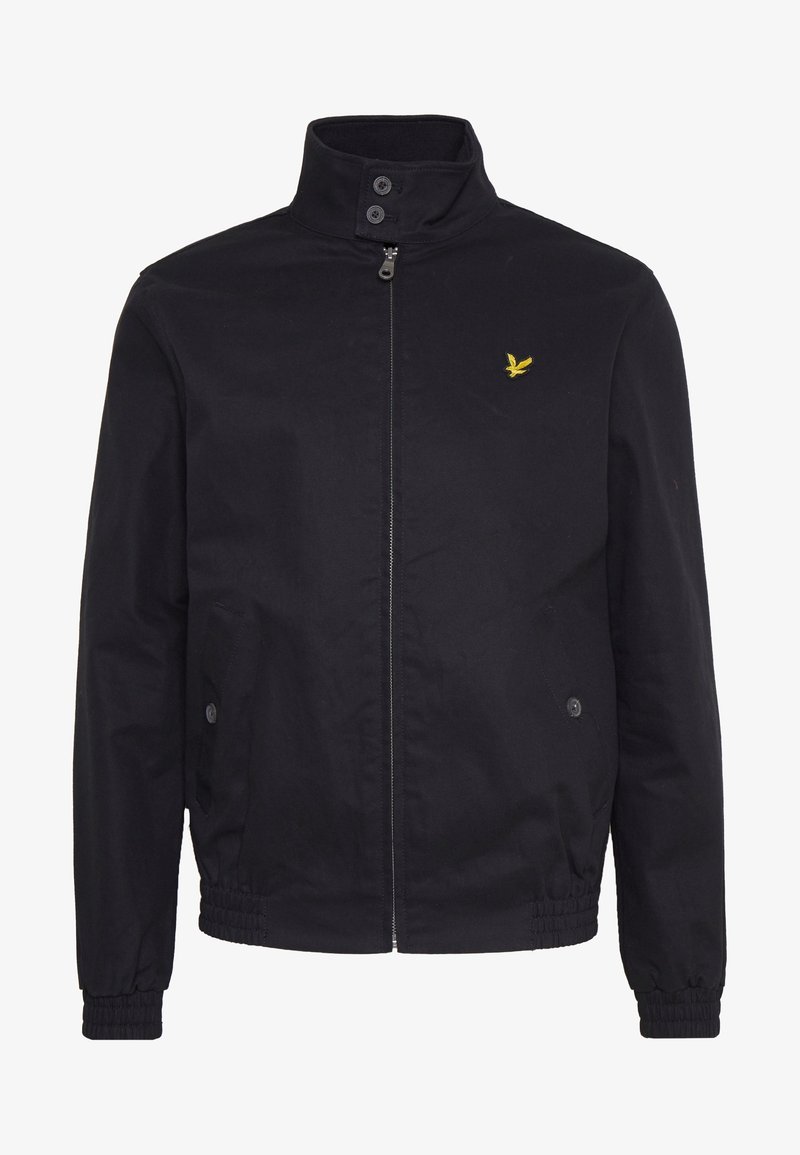 Schwarze Zip-Jacke mit hohem Kragen, Knopfdetails, elastischen Bündchen und Saum sowie kleinem gelben Vogel-Logo auf der linken Brust.