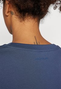 T-shirt blu scuro con scollo rotondo, texture morbida, con la scritta in rilievo "ONLY PLAY" sul colletto posteriore.