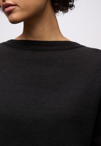 Zwarte gebreide trui met een gestructureerde, geribbelde halslijn. Heeft een zachte, gladde stof en een ontspannen pasvorm, met een minimalistisch ontwerp.