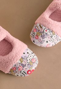 Ružové chlpaté papuče s jemným zvrškom a vzorovaným textilným špičkovým dielom s kvetinovými motívmi a hracími kartami, ktoré pôsobia pohodlne.
