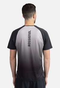 Krátký rukáv sportovní tričko, gradient od tmavě šedé po světlou šedou, texturovaný design s kruhovými perforacemi, obsahuje logo "ROSSIGNOL" na zadní straně.