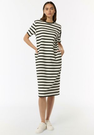 Striped dress in black and white, featuring a relaxed fit, short sleeves, side pockets, and a round neckline. Worn with white sneakers.