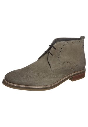 Miesten taupenvärinen mokkainen siipikuvioinen nilkkuri, jossa on brogue-yksityiskohdat, mustat kengännauhat ja ruskea kerrostettu korko.