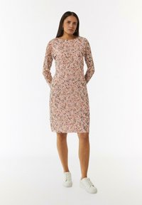 Blumenkleid mit langen Ärmeln, rundem Ausschnitt und Taschen. Das Muster umfasst pinke und schwarze Blumen auf einem hellen Hintergrund.
