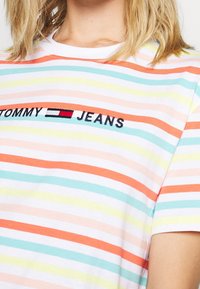 Gestreepte t-shirt in roze, oranje, groen en blauw. Bevat geborduurd "TOMMY JEANS" logo. Korte mouwen, ronde hals, van katoen.