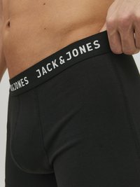 Schwarze Baumwollunterwäsche mit einem breiten schwarzen Bund, auf dem das Logo "JACK & JONES" in Weiß gedruckt ist. Enganliegendes Design mit glatter Textur.
