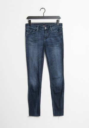 Jeans de mezclilla azul oscuro con corte ajustado, que cuentan con una cintura clásica, bolsillos frontales y un ligero deshilachado en el dobladillo.