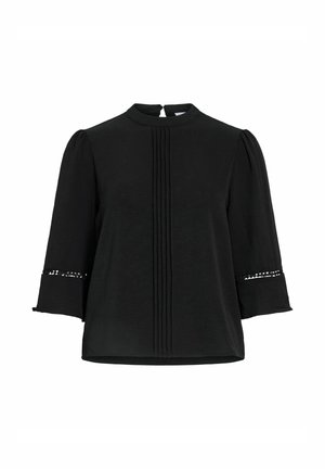 Juoda palaidinė su klostuotu priekiu, trijų ketvirčių pūstomis rankovėmis ir nėrinių detalė virš plačių rankogalių, su mažu mygtuko užsegimu nugaroje.