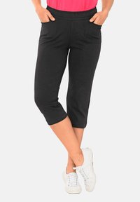 Schwarze Caprihosen aus weichem Stoff, mit einem elastischen Bund und zwei Vordertaschen, die unter dem Knie enden.