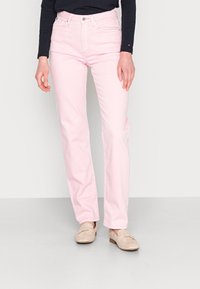 Jeans de mezclilla rosa con un diseño de pierna recta, que presentan un estilo clásico de cinco bolsillos y detalles de costura sutiles. Combinados con zapatos beige.