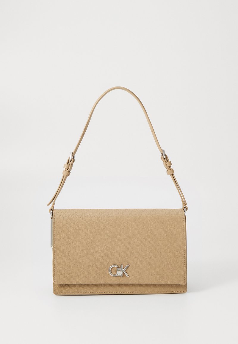 Beige crossover-veske med preget mønster, kjede-rem, magnetisk lukking og sølvfarget detaljer. Glatt tekstur med en strukturert form.