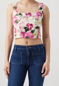Blommig crop top med fyrkantig halsringning, med rosa blommor på en krämfärgad bakgrund. Matchad med tighta mörka jeans i denim med fickor.