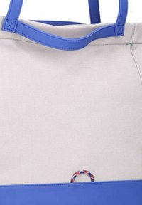 Canvas draagtas met blauwe synthetische banden, een crèmekleurig lichaam en een accentdetail aan de voorkant met een rood, wit en blauw patroon.