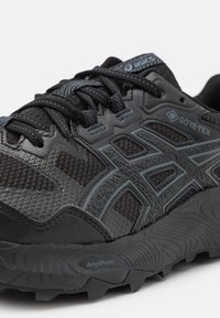 Sapatilha de corrida preta com parte superior em malha e sintético, marca Gore-Tex, detalhes texturizados e sola AmpliFoam para tração e amortecimento.