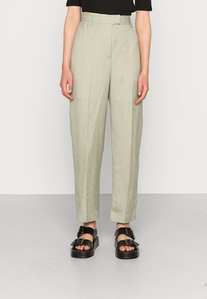 Vaaleanvihreät korkeavyötäröiset housut, joissa on rento malli, etupleisit ja sileä pinta, yhdistettynä mustiin platform-sandaaleihin.