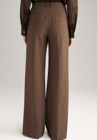 Pantalon marron taille haute à jambes larges porté avec un chemisier marron à manches longues assorti, vu de dos.