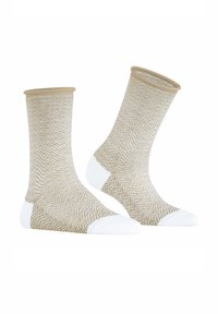 Beige Socken mit einem weißen Zickzack-Muster, versehen mit einem kontrastierenden Bündchen am oberen Rand und weißer Verstärkung an den Zehen und Fersen.